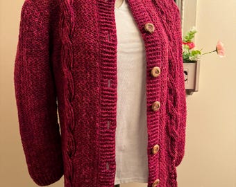 May include: A long-sleeved, burgundy cardigan with a cable knit pattern and wooden buttons.