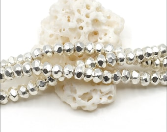 May include: A strand of metallic silver-colored beads with a faceted, irregular surface texture. The beads are strung together in a continuous line, displaying a reflective, shiny finish across each individual bead's multifaceted geometric shape.