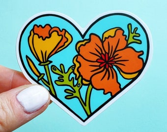 May include: A heart-shaped sticker with a blue background and two orange flowers. The flowers are stylized and have a black outline. The sticker is perfect for adding a touch of whimsy to any surface.