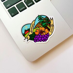 May include: A heart-shaped sticker with a colorful illustration of a rural landscape, a red barn, a flower, and grapes. The text "Sonoma County" is written in a yellow banner.