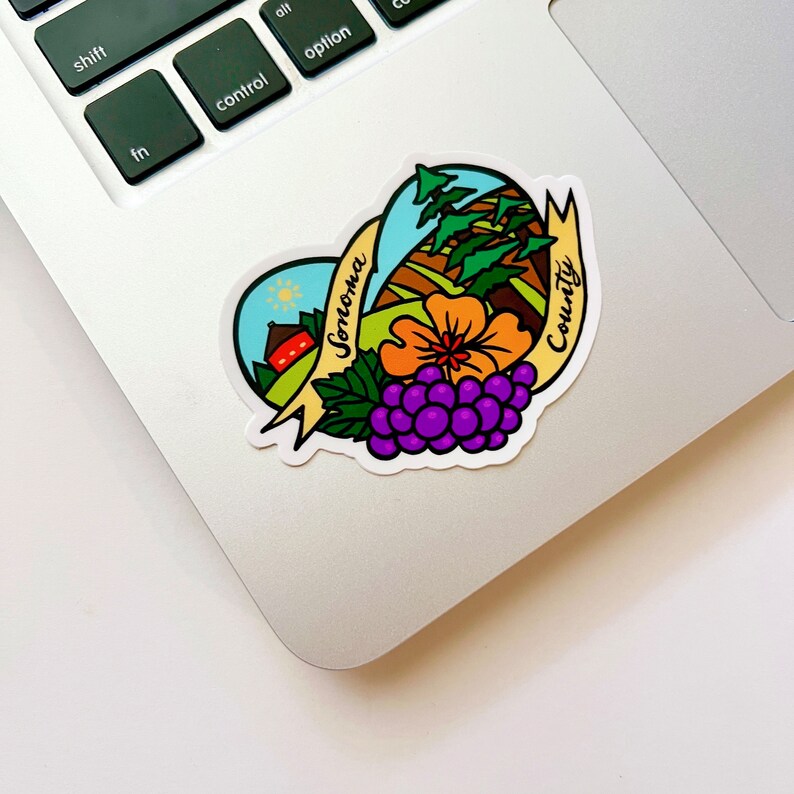 May include: A heart-shaped sticker with a colorful illustration of a rural landscape, a red barn, a flower, and grapes. The text "Sonoma County" is written in a yellow banner.
