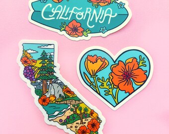 May include: Three colorful stickers with a California theme. One is a teal surfboard shape with the word "CALIFORNIA" in white script, surrounded by orange flowers. Another is a heart shape with orange flowers. The third is a California state outline with a landscape.