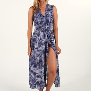 Pode incluir: Um vestido maxi comprido, sem mangas, azul e branco tie-dye, com decote em V e fecho de envoltório. O vestido tem uma fenda lateral e um laço na cintura.