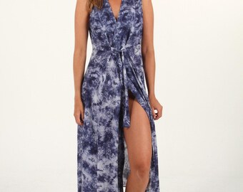 May include: A long, sleeveless, blue and white tie-dye maxi dress with a V-neckline and a wrap-style closure. The dress has a side slit and a tie at the waist.