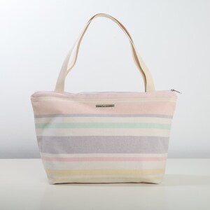 May include: A striped tote bag with a zipper closure. The bag is made of canvas and has a light pink, yellow, green, and purple striped pattern.