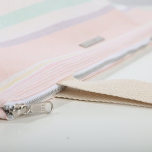 May include: A pink and white striped canvas tote bag with a zipper closure and a beige canvas strap.
