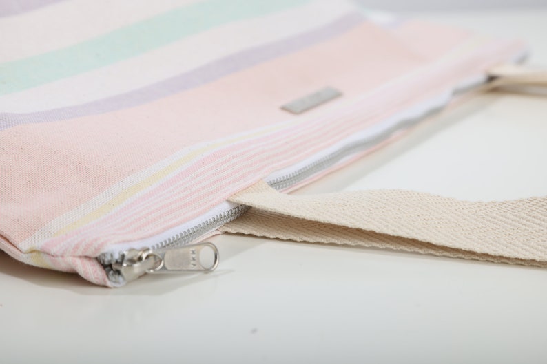 May include: A pink and white striped canvas tote bag with a zipper closure and a beige canvas strap.
