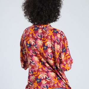 May include: A red, pink, and yellow floral print shirt with a button-up collar. The shirt has a relaxed fit and is made of a lightweight fabric.