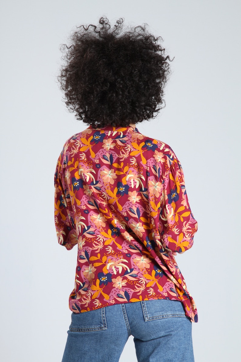 May include: A red, pink, and yellow floral print shirt with a button-up collar. The shirt has a relaxed fit and is made of a lightweight fabric.
