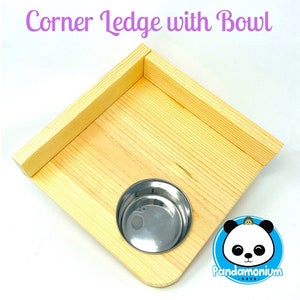 May include: A wooden corner ledge with a stainless steel bowl. The ledge is made of light-colored wood and has a square shape. The text "Corner Ledge with Bowl" is at the top. A logo with a panda is in the bottom right corner.