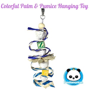 Puede incluir: Un colorido juguete colgante para mascotas, con piedras pómez, cuentas de madera y cintas trenzadas azules y blancas. El juguete incluye pequeños bloques de madera con las letras "Z" y "H". El texto "Colorful Palm & Pumice Hanging Toy" está en la parte superior.