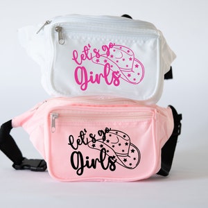 May include: Two fanny packs, one white and one pink, with the text "let's go girls" and a pink cowboy hat with stars on it.