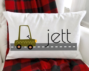 Könnte beinhalten: Ein weißes Kissen mit einem grünen Comic-Auto, das auf einer grauen Straße fährt, mit dem Namen "Jett" in Schwarz geschrieben.