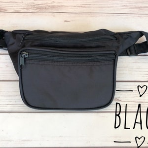 May include: Black fanny pack with two zippered compartments and a black strap. The text "BLACK" is written on the bottom of the image.