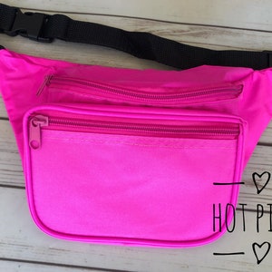 May include: Hot pink fanny pack with a black adjustable strap and two zippered compartments. The text "HOT PINK" is written on the front of the pack.