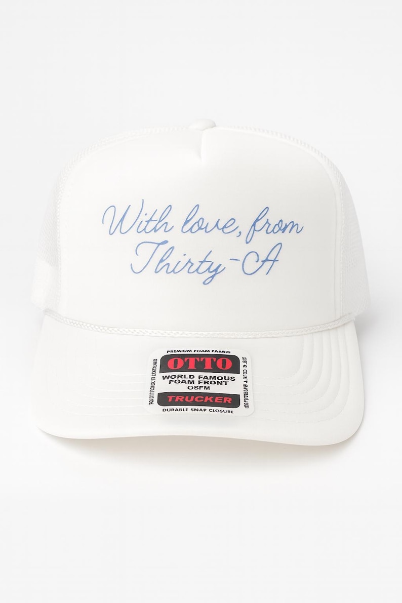 Puede incluir: Gorra de camionero blanca con parte trasera de malla y frontal de espuma. La gorra presenta el texto "With love, from Thirty-CA" en escritura azul. Una etiqueta indica "OTTO" y "TRUCKER".