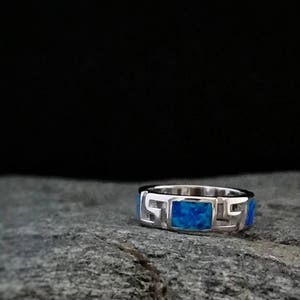 Può includere: Un anello d'argento con una pietra di opale blu incastonata in un design geometrico.