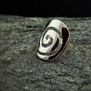 May include: A silver ring with a spiral design. The ring is made of a smooth, shiny metal and has a simple, elegant look.