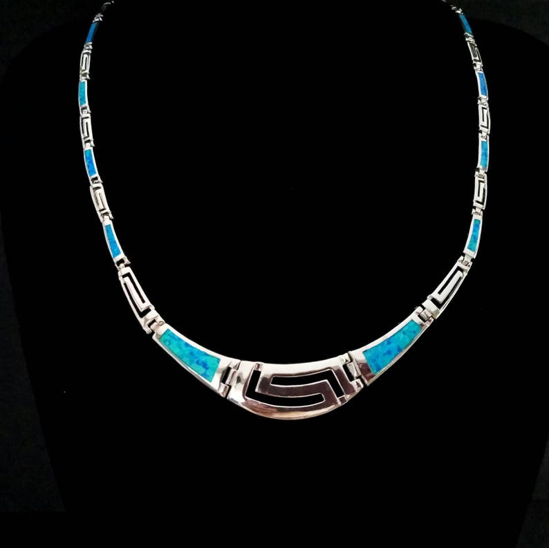 May include: A silver necklace with a blue opal inlay in a geometric pattern. The necklace is made of sterling silver and features a unique design.
