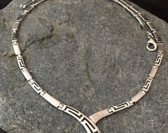 May include: A silver necklace with a geometric pattern. The necklace is made of interlocking squares and is about 18 inches long.