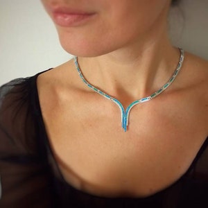 Peut inclure: Un collier en argent avec un pendentif en forme de V serti de pierres turquoise.