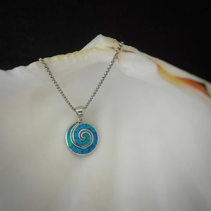 May include: A silver chain necklace with a blue and green opal pendant featuring a spiral design.