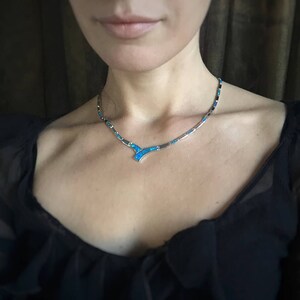 May include: A silver necklace with a blue opal pendant. The necklace is made of small, rectangular pieces of opal set in silver.