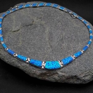Puede incluir: Un collar de plata con un centro de &oacute;palo azul. El collar est&aacute; hecho de peque&ntilde;os eslabones rectangulares y tiene un dise&ntilde;o simple y elegante.