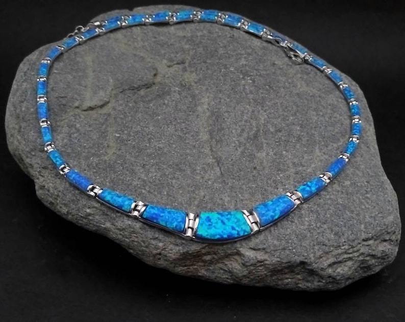 Puede incluir: Un collar de plata con un centro de &oacute;palo azul. El collar est&aacute; hecho de peque&ntilde;os eslabones rectangulares y tiene un dise&ntilde;o simple y elegante.