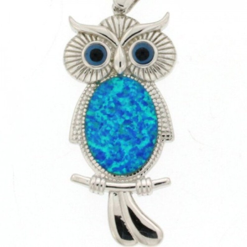 K&ouml;nnte beinhalten: Silberner Eulens Anh&auml;nger mit einem blauen Opal-Stein. Die Eule sitzt auf einem Ast mit ausgebreiteten Fl&uuml;geln.