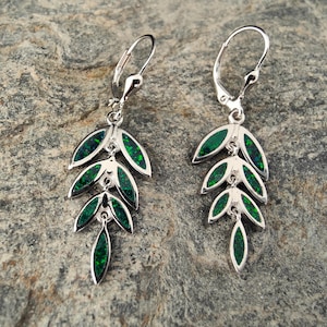 May include: A pair of silver dangle earrings with green opal leaves. The earrings have a leverback closure.