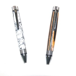 May include: Two pens with silver accents. One pen has a white and black marbled design. The other pen has a brown and black wood grain design.