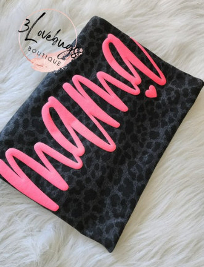 May include: Black and grey leopard print t-shirt with the word "mama" in pink lettering.