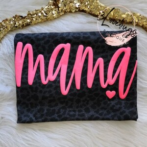 May include: Black and white leopard print t-shirt with the word "mama" in pink lettering and a small pink heart.