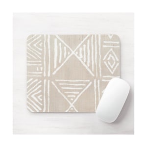 May include: A beige mouse mat with a white geometric pattern. The pattern is made up of triangles, squares, and lines. The mouse mat is on a white wooden surface.
