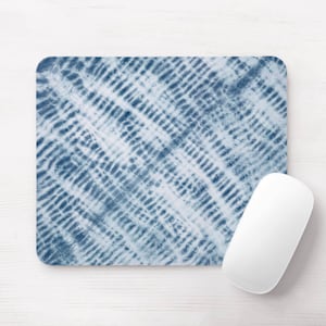May include: A rectangular mouse mat featuring a blue and white tie-dye design, alongside a white wireless mouse. The mouse mat has rounded corners and a textured pattern. The mouse is smooth and ergonomic.