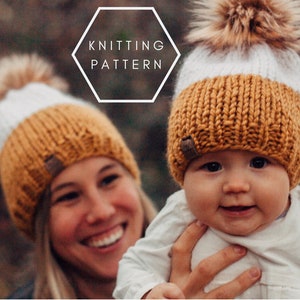 May include: A close-up of a mother and child wearing matching knitted hats with white and mustard yellow stripes and faux fur pom-poms. The hats have a brown leather label with the word "Knitting Pattern" on it.