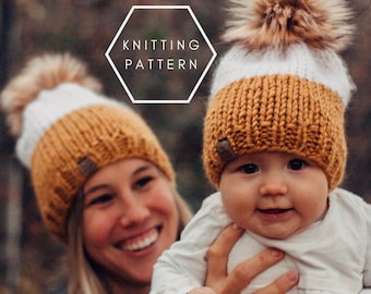 May include: A close-up of a mother and child wearing matching knitted hats with white and mustard yellow stripes and faux fur pom-poms. The hats have a brown leather label with the word "Knitting Pattern" on it.