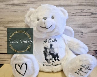 May include: White teddy bear with angel wings, a photo of an older couple, and the text "A Cuddle From Heaven" and "Lots of Love Mum and Dad".