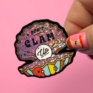May include: A die-cut sticker shaped like an open clam shell with a white pearl in the center. The shell features a purple interior with pink glitter accents and the text "DON'T CLAM UP" in black. The exterior of the shell has teal, yellow, and red stripes.