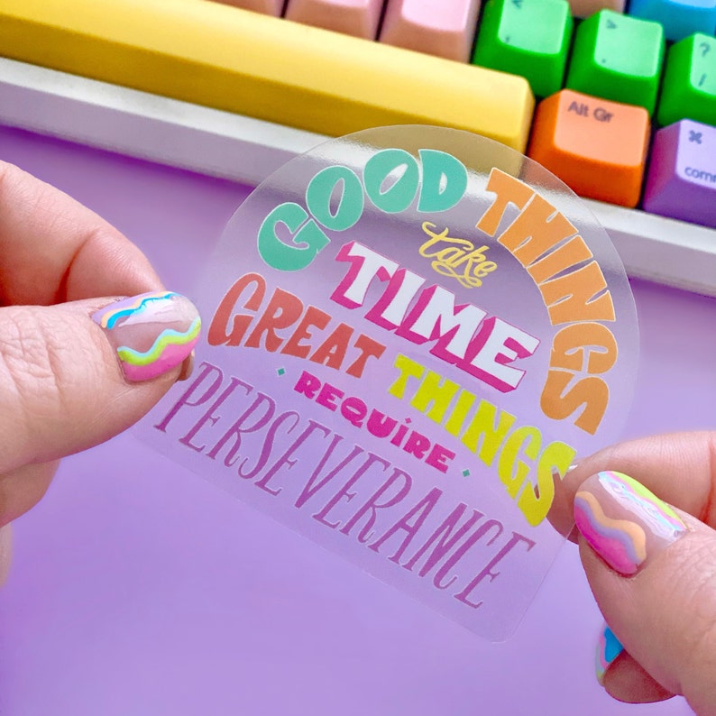 May include: A clear sticker with a rainbow arch design and the text "Good things take time, great things require perseverance".