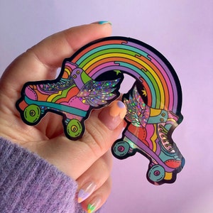 May include: A rainbow sticker featuring two roller skates with wings. The skates are rainbow coloured and have glitter accents. The rainbow also has glitter accents.