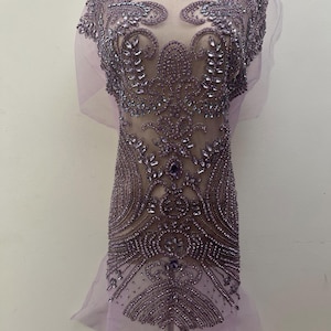 May include: A lavender-colored fabric with intricate beadwork and embellishments. The design features floral and geometric patterns, with sparkling crystals and beads. The fabric is sheer, with a delicate, flowing appearance. The number "093#" is visible in the upper left corner.
