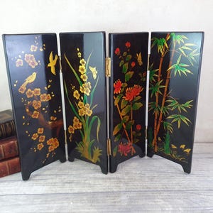 May include: A black folding screen with four panels. Each panel features a different design with gold and red accents. The designs include birds, flowers, and bamboo.