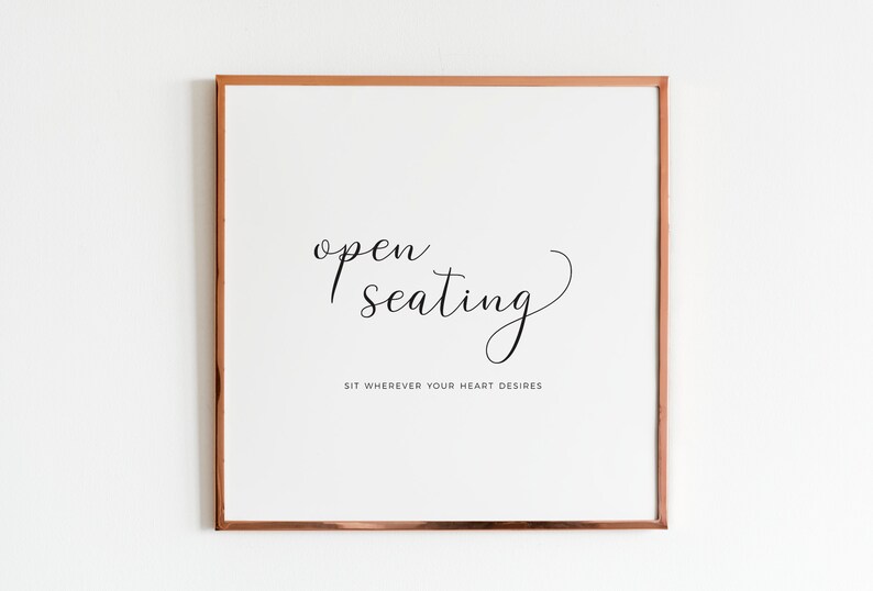 May include: Square framed print with the words "open seating" in elegant script. Below, the text reads "Sit wherever your heart desires." The frame is a warm copper color, and the background is white.