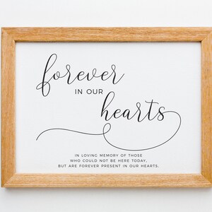 May include: A framed print with the text "forever in our hearts" in a cursive font. The text is in black on a white background. Below the text is a smaller text that reads "In loving memory of those who could not be here today, but are forever present in our hearts."