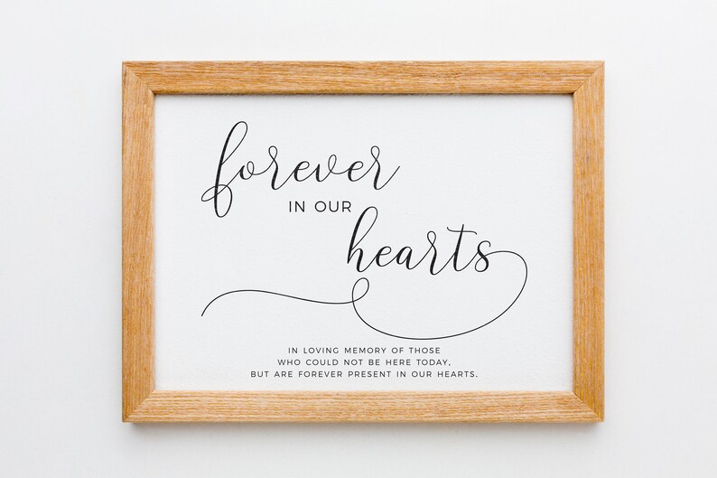 May include: A framed print with the text "forever in our hearts" in a cursive font. The text is in black on a white background. Below the text is a smaller text that reads "In loving memory of those who could not be here today, but are forever present in our hearts."
