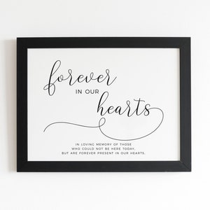 May include: Black framed print with a white background and black text that reads "forever in our hearts" and "In loving memory of those who could not be here today, but are forever present in our hearts."