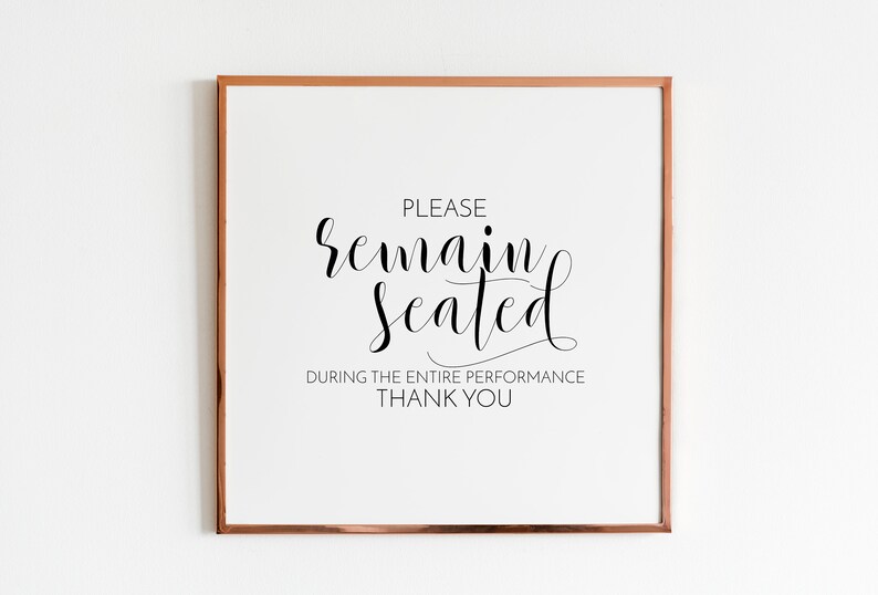May include: A white sign with a black frame and the text "PLEASE remain seated DURING THE ENTIRE PERFORMANCE THANK YOU".