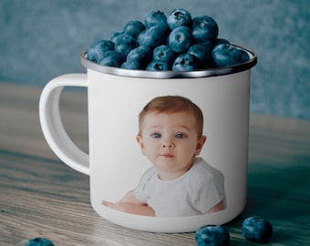 May include: White enamel mug with a photo of a baby in a white shirt. The mug is filled with blueberries.